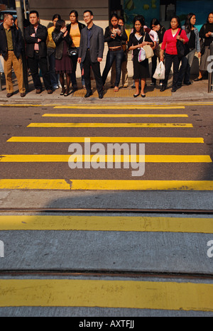 Le persone in attesa di attraversare a luci di strada, Hong Kong. Foto Stock