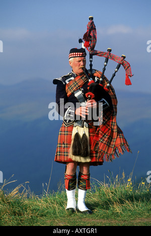 Bagpiper a Loch Ginestra nelle Highlands scozzesi Foto Stock