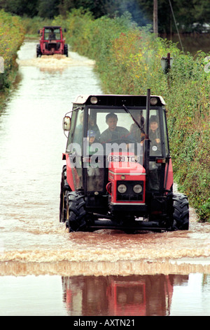 Gli agricoltori guidare i loro trattori attraverso vicoli allagati vicino a Caerleon Wales UK dopo il fiume Usk burst si tratta di banche in seguito heavy rain Foto Stock
