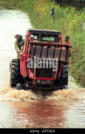 Gli agricoltori guidare i loro trattori attraverso vicoli allagati vicino a Caerleon Wales UK dopo il fiume Usk burst si tratta di banche in seguito heavy rain Foto Stock