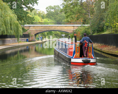 Un uomo percorre una narrowboat sul Regents Canal London Inghilterra England Foto Stock