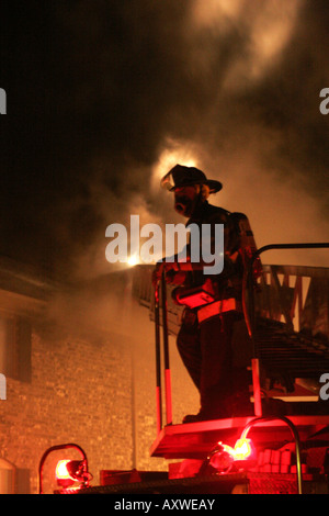 Un vigile del fuoco sulla parte superiore della scaletta carrello dopo proveniente dal tetto di un palazzo di appartamenti che era in fiamme Foto Stock