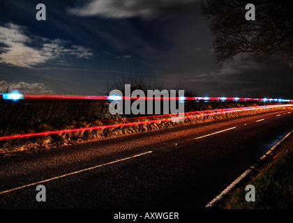 Chiamata di emergenza - un auto della polizia di luci lampeggianti sentiero sulla strada di un paese di notte Foto Stock