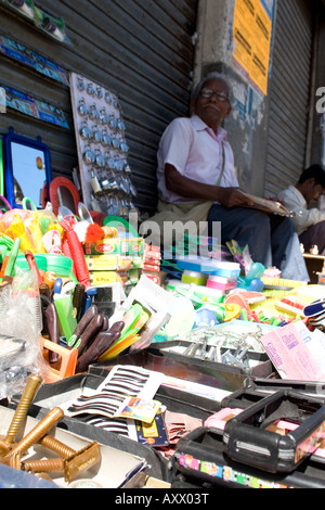 Un uomo si siede e vende merci dalla strada nel centro di Mysore. Foto Stock