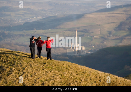 Ragazzi giocare su una collina alla Mam Tor nei pressi di Castleton, parco nazionale di Peak District, Blue Circle Cement Factory è in background Foto Stock