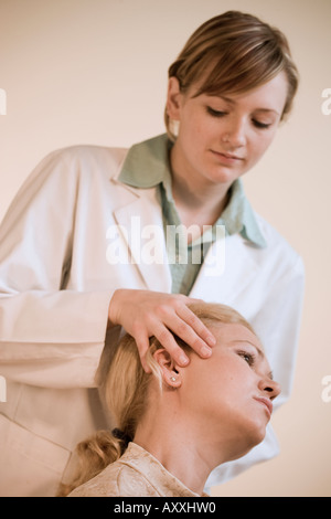 Chiropratico femmina regola la testa, il collo e la colonna vertebrale del paziente femmina. Foto Stock