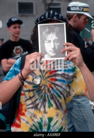 Un giovane uomo detiene una foto di John Lennon in una celebrazione di ciò sarebbe Lennon s cinquantesimo compleanno il 9 ottobre 1990 Foto Stock