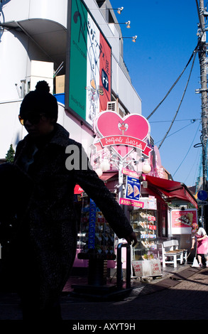 Giovane donna camminare lungo le strette Tokyo shopping street Foto Stock