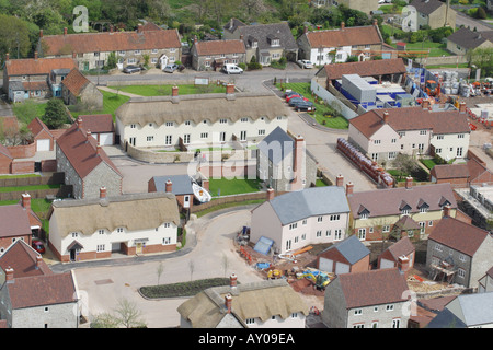Vista aerea del moderno sviluppo di alloggiamento in uno stile tradizionale a fianco di borgo vecchio alloggiamento in un villaggio rurale Somerset Foto Stock