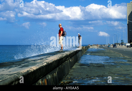 Gli stranieri in piedi sul mare di parete il Malecon a l'Avana Foto Stock