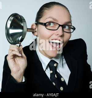 Studio shot ritratto di una bella curioso business donna in un costume tuta hearing aid imbuto curioso spionaggio gossip Foto Stock