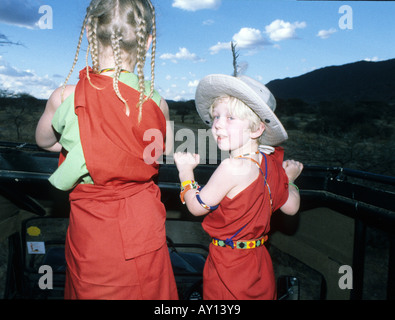 Bambini occidentali nel Samburu/Masai abiti sul Land Rover game drive al tramonto Foto Stock