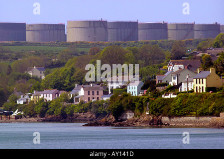 Villaggio di Llanstadwell dominato da grandi serbatoi di stoccaggio di una raffineria di petrolio Pembrokeshire Wales UK Foto Stock