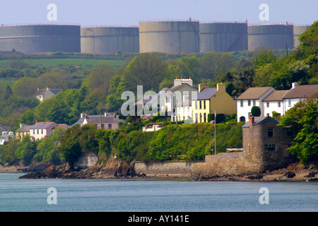 Villaggio di Llanstadwell dominato da grandi serbatoi di stoccaggio di una raffineria di petrolio Pembrokeshire Wales UK Foto Stock