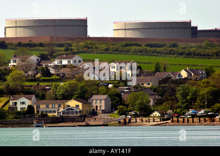 Villaggio di Llanstadwell dominato da grandi serbatoi di stoccaggio di una raffineria di petrolio Pembrokeshire Wales UK Foto Stock