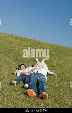 Il padre e i bambini che dormono nel campo Foto Stock
