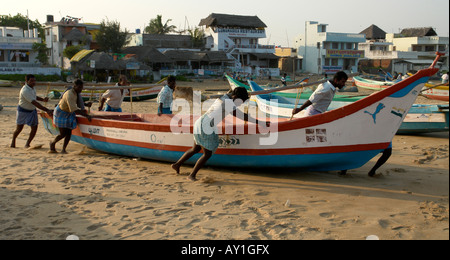 I pescatori indiani spingendo la loro tradizionale barca da pesca lungo la spiaggia verso il mare a mamallapuram Foto Stock