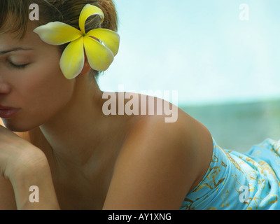 Il profilo laterale di una giovane donna che indossa fiori (Plumeria) nei suoi capelli Foto Stock