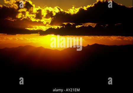 Sunset sunrise rompe attraverso le nuvole e le montagne Foto Stock