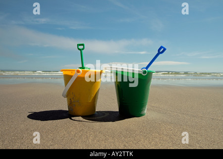 Due secchi di sabbia in spiaggia con pale Foto Stock