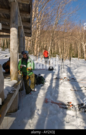 Gli sciatori si prendono una pausa e consultare una mappa a un log cabin durante una sci backcountry viaggio a Gerusalemme Vermont Foto Stock