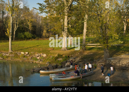 Un gruppo di preteen i ragazzi e le ragazze si preparano a entrare in alluminio tre canoe spiaggiata sulla banca del fiume di Concord Foto Stock