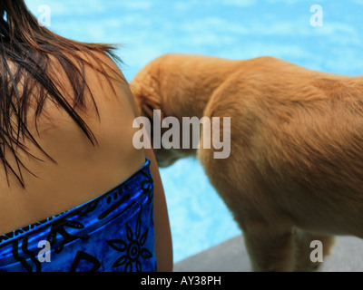 Metà vista in sezione di una giovane donna con un golden retriever cane a bordo piscina Foto Stock