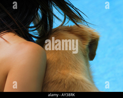 Close-up di una giovane donna a bordo piscina con un golden retriever cane Foto Stock