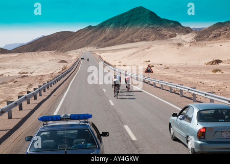 Ciclo internazionale di corsa lungo la strada del deserto con la polizia stradale automobile visto attraverso la finestra del veicolo nel deserto del Sinai Egitto Foto Stock