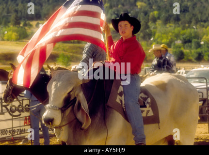 Un giovane cowboy sventola la bandiera per la American inno nazionale, all'annuale 4-H Rodeo tenutasi a Capitan, Nuovo Messico. Foto Stock