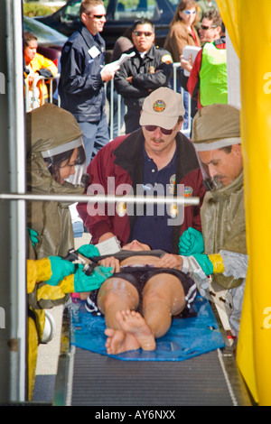 Indossando biologiche chimica indumenti tecnici medici pulire un volontario vittima in una tenda di decontaminazione in drill Foto Stock