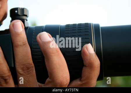 Dettaglio del fotografo manipolazione di un avanzato sistema di telecamera professionale con obiettivo zoom per scattare foto all'aperto Foto Stock