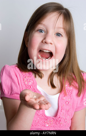 Bambina eccitato che mostra un dente recentemente caduto, insieme con il gap nella sua bocca. Foto Stock