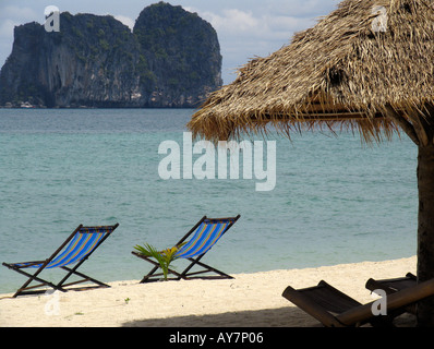 La sterpaglia ombrellone sedie a sdraio alla spiaggia di sabbia bianca isolotto roccioso Ko Ngai isola della Thailandia Foto Stock