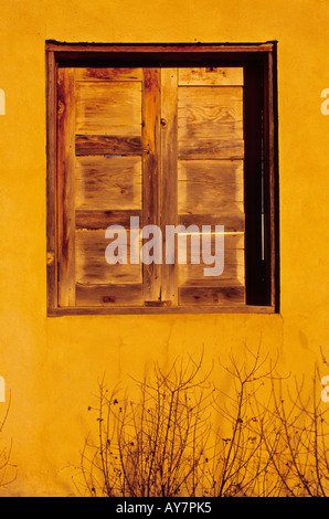 Adobe e parete in legno finestra ritagliata nelle ombre di un ritiro spirituale Benedettina di San Patricio, Nuovo Messico. Foto Stock