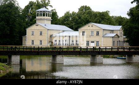 Grandi edifici in legno con ponte di legno in primo piano. Riflessioni di edifici in acqua, gli alberi come sfondo Foto Stock