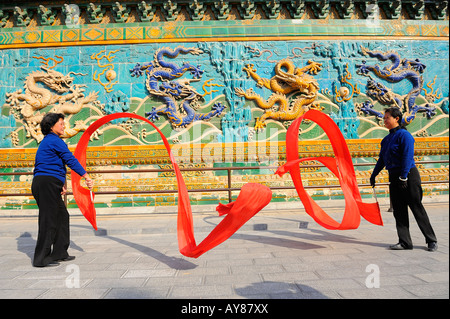 Le donne cinesi ballando con tessuti di seta rossa nella parte anteriore del nove draghi muro al Parco Beihai a Pechino in Cina. 05-Mar-2008 Foto Stock