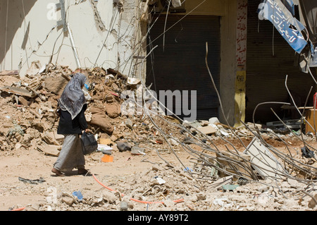 La donna a piedi nella zona di guerra Foto Stock