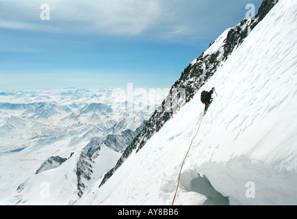 Scalatore è salendo lungo il pendio a monte attraverso il crack glaciale La montagna Belukha la cresta Katunskiy Altai Russia Foto Stock