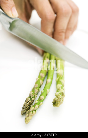 La donna gli asparagi di taglio con il coltello, vista ritagliata della mano Foto Stock