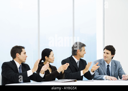 I dirigenti ad applaudire collega di sesso maschile durante la riunione Foto Stock