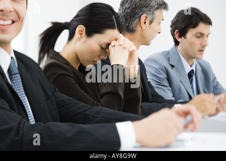 I dirigenti di business meeting, donna di chiudere gli occhi e la testa pendente contro le mani Foto Stock