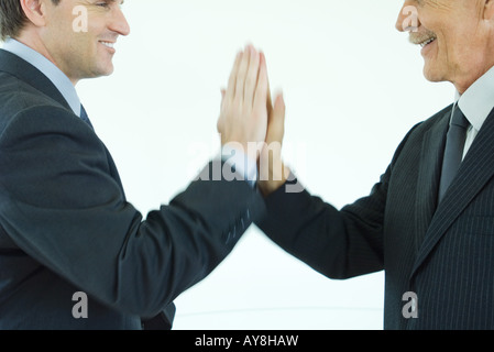 Due imprenditori dando a ogni altro ad alta cinque, ritagliato vista laterale Foto Stock