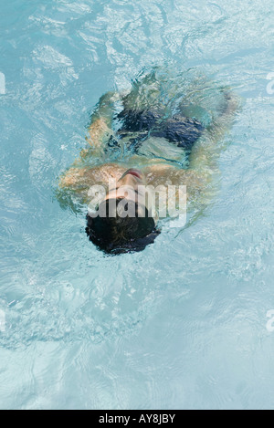 L'uomo galleggiante sul retro in piscina, vista posteriore Foto Stock