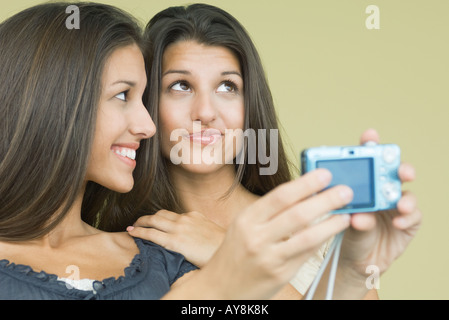 Ragazza adolescente fotografare auto e sorella gemella con fotocamera digitale, sia guardando lontano, close-up Foto Stock