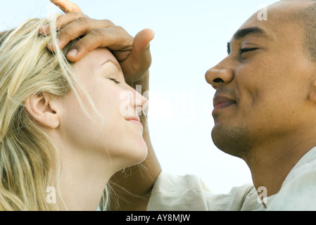 Collocando man mano sulla donna di fronte, entrambi con gli occhi chiusi, vista laterale Foto Stock