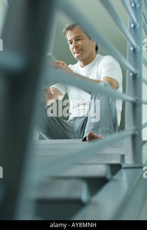 Uomo seduto sulle scale libro di lettura a basso angolo di visione Foto Stock