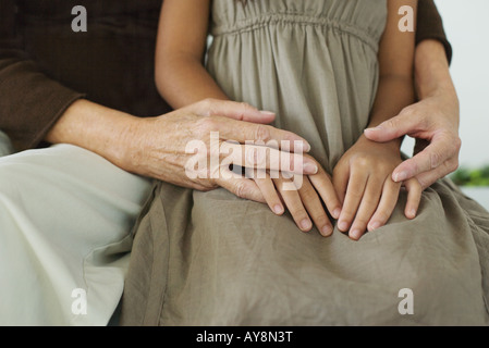 Donna abbracciando la nipote, mani giunte, vista ritagliata Foto Stock