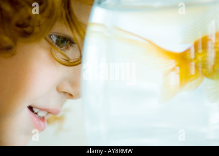 Bambina guardando goldfish in fishbowl, close-up Foto Stock