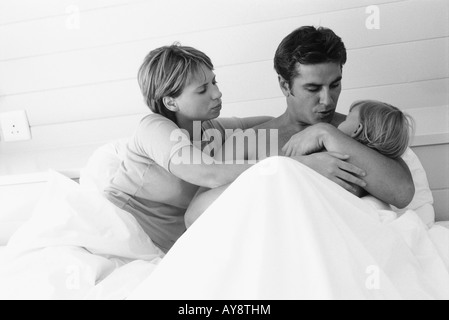 Coppia giacendo in letto, uomo con bambino in armi Foto Stock